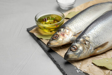 Slate plate with salted herrings, oil and spices on grey table, closeup. Space for text