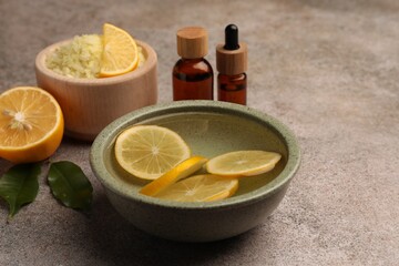 Essential oil with lemons and sea salt on grey textured table. Aromatherapy treatment