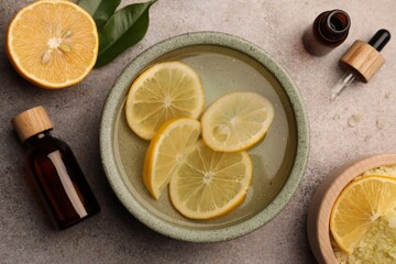 Flat lay composition with essential oil and lemons on grey textured table. Aromatherapy treatment