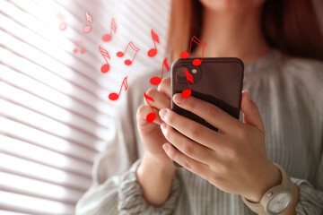 Woman listening to music on mobile phone indoors, closeup. Music notes illustrations flowing from...