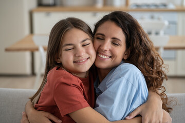 Friendly happy woman and teen girl hug and rejoice at meeting after long separation or going on...