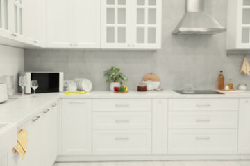 Fototapeta na wymiar White cosy kitchen with furniture, blurred view. Interior design