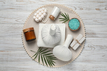 Composition of herbal bags and spa products on white wooden table, top view
