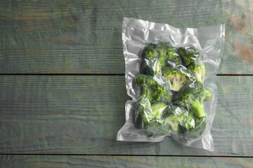 Vacuum pack of broccoli on wooden table, top view. Space for text