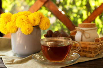 Beautiful yellow chrysanthemum flowers and cup of aromatic tea on wooden table