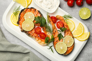 Tasty grilled salmon steaks and ingredients on light grey table, flat lay