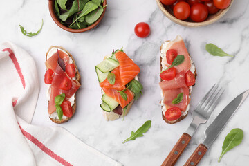Flat lay composition with different tasty bruschettas served on white marble table