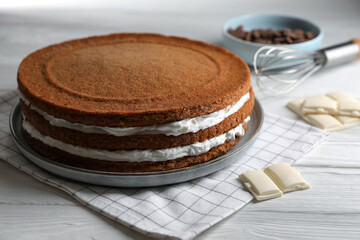 Delicious homemade layer cake and chocolate on white wooden table, closeup