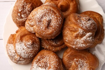 Delicious profiteroles with powdered sugar on white table, top view