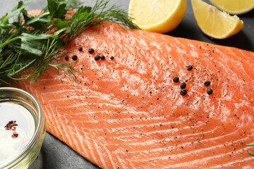 Fresh raw salmon and ingredients for marinade on black table, closeup