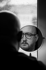 A reflection of a fragment of a man's face with a beard visible in the mirror.