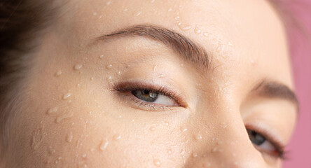 Girl's face with water drops on her face Looks at the camera Blue eyes Close up Horizontal frame...