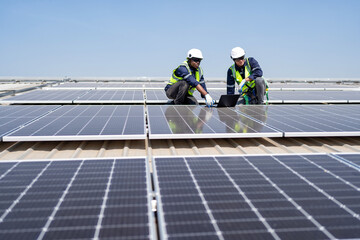 Engineer on rooftop kneeling next to solar panels photo voltaic check laptop for good installation