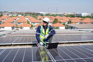 Engineer on rooftop kneeling next to solar panels photo voltaic check laptop for good installation