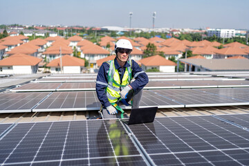 Fototapeta premium Engineer on rooftop kneeling next to solar panels photo voltaic check laptop for good installation