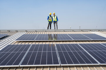 Engineer on rooftop stand next to solar panels happy inspection after installation completed