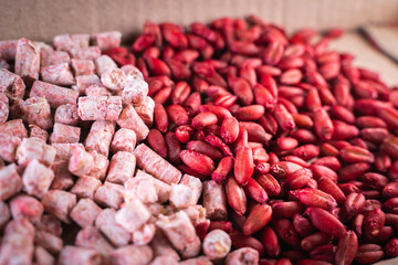 Two different poisons from rodent pests close-up on a cardboard backing. Red wheat and pink pellets...