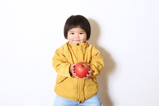 りんごを持った女の子。おかっぱヘアーの二歳児。