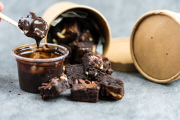 Eating squares brownies with dip chocolate sauce by wood spoon