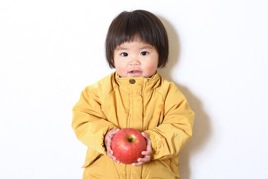 りんごを持った女の子。おかっぱヘアーの二歳児。