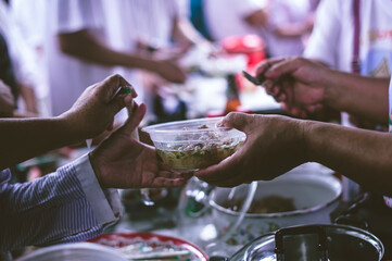 Volunteer's hands offer shared food to the poor to alleviate hunger : humanitarian aid concept.