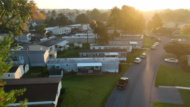 American Flag Hangs At Mobile Home Park In USA. Aerial View In Warm Golden Hour Light. Low Income Housing In America Theme.