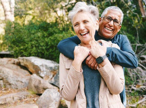 Hiking, laugh and romance with a senior couple hugging while in the woods or nature forest together in summer for a hike. Fun, joke and bonding with a mature man and woman enjoying retirement outdoor