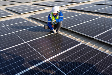 Engineer on rooftop kneeling next to solar panels photo voltaic with tool in hand for installation