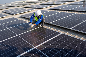 Engineer on rooftop kneeling next to solar panels photo voltaic with tool in hand for installation