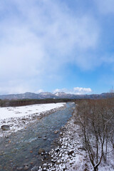 蓮華大橋（長野県）から撮影した、雪が積もった河原と川と壮大な山の風景写真（縦写真） - obrazy, fototapety, plakaty