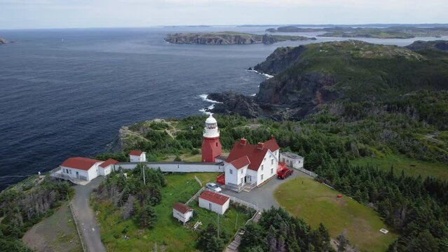 A tilt down pass over of the Long Point Lighthouse and cliffs at Crow Head, near Twillingate, Newfoundland and Labrador