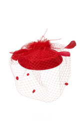 Close-up shot of a red felt pillbox hat with a veil decorated with feathers. The hat with an alligator clip is isolated on a white background. Front view.