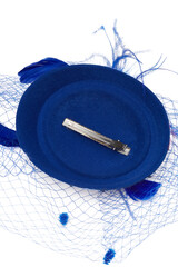 Close-up shot of a dark blue felt pillbox hat with a veil decorated with feathers. The hat with an alligator clip is isolated on a white background. Bottom view.