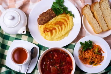 dinner set, mashed potatoes with a cutlet, a plate of soup, salad, tea and bread