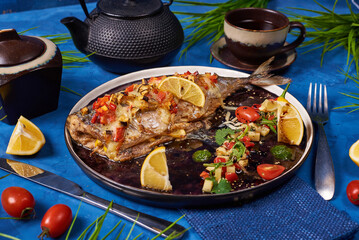 fried fish with vegetables on a blue background