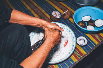 Traditional hand scraping of coconut flesh in Thailand