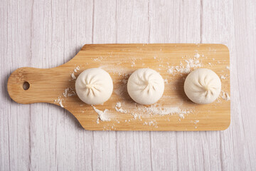 Raw khinkali on a wooden board on a white background