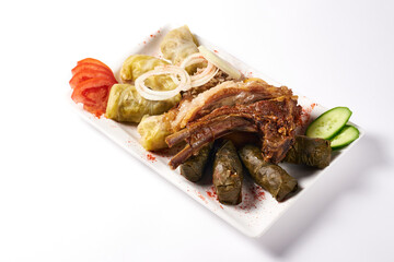 cabbage rolls and lamb ribs with meat, tomatoes and cucumbers with onions. on a white background