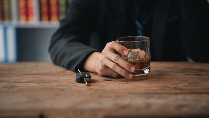 Man holding a glass of brandy, he is drinking brandy in a bar, drinking alcohol impairs driving ability and can damage health. The concept of drinking alcohol.