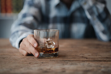 Man holding a glass of brandy, he is drinking brandy in a bar, drinking alcohol impairs driving ability and can damage health. The concept of drinking alcohol.