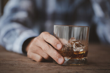 Man holding a glass of brandy, he is drinking brandy in a bar, drinking alcohol impairs driving ability and can damage health. The concept of drinking alcohol.