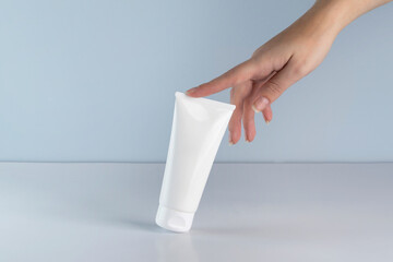 A woman's hand holding a tube of white cream. Cosmetics mockup.