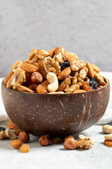 Raw mixed nuts on gray background. Walnuts, almonds, hazelnuts and raisins in a coconut bowl. close up