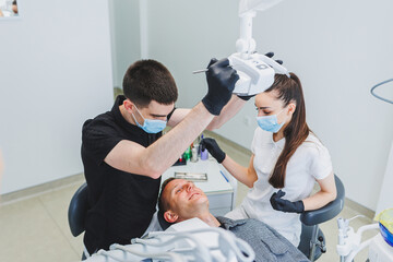 Dental office, examining a patient in a dental chair. Dental treatment is performed by a doctor and an assistant. Dental care.