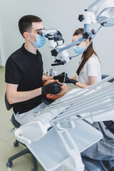 Modern dental office with a microscope. A dentist treats a man's teeth under a microscope, an assistant helps him. Modern medical care for toothache