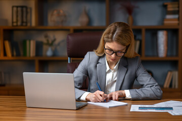 Fototapeta premium Portrait of businesswoman with laptop writes on a notebook at her office