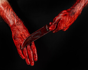 A man wipes a bloody knife with his hand on a black background.  © Михаил Решетников