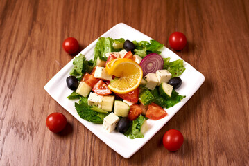 salad of cucumbers, tomatoes, feta cheese, onions, olives, greens, lemon