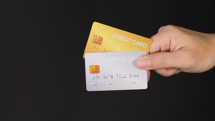 Hand is hold two credit cards. Gold and silver color credit cards isolated on black background.