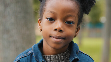 Little African American girl outdoors close-up child pretty smiling looking at camera ethnic...